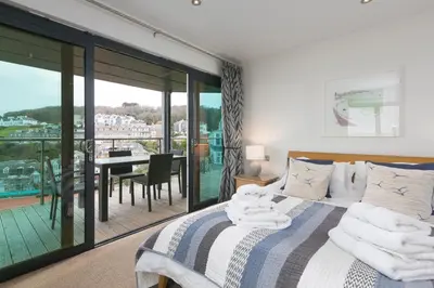 a bedroom with a bed and a balcony with a table at Stargazy in St Ives