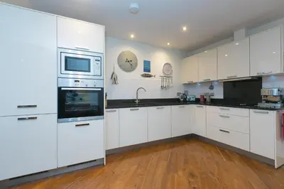 a kitchen with white appliances and wooden floors at Stargazy in St Ives