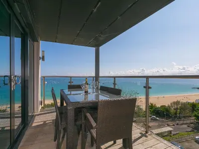 a table and chairs on a balcony with a view of the beach at Stargazy in St Ives