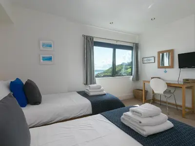 a bedroom with two beds and a desk and a window at Stargazy in St Ives