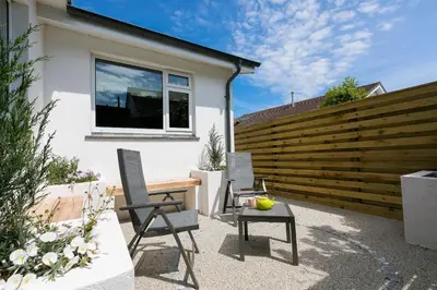 a patio with chairs and a table in front of a fence at Secret Beach in Carbis Bay