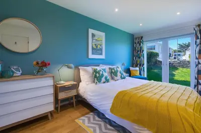 a blue bedroom with a bed and a mirror at Secret Beach in Carbis Bay