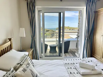 a bedroom with a bed and a balcony with a tub at 5 The Beach House in Saint Columb Minor