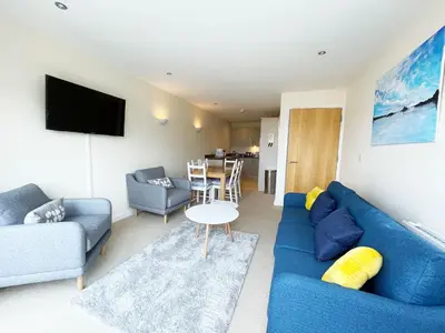 a living room with a blue couch and a table at 5 The Beach House in Saint Columb Minor