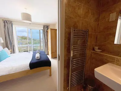 a bedroom with a bed and a bathroom with a shower at 5 The Beach House in Saint Columb Minor