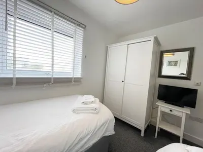 a white bedroom with a bed and a tv at 33 Ocean one in Newquay