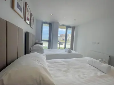 two white beds in a room with a window at 38 Zinc in Newquay