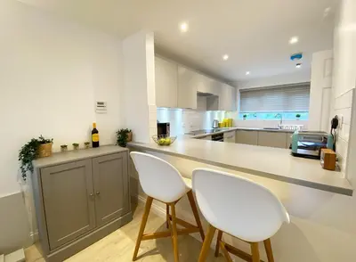 a kitchen with two white chairs and a counter at 3 Harvest Moon in Newquay