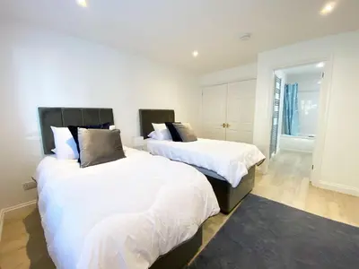 two beds in a bedroom with white sheets and pillows at 3 Harvest Moon in Newquay