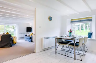 a dining room and living room with a table and chairs at Goose Cottage - within the Helland Barton Farm collection in Delabole