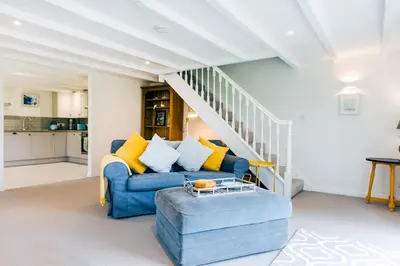 a living room with a blue couch and yellow pillows at Goose Cottage - within the Helland Barton Farm collection in Delabole