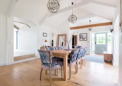 a dining room with a wooden table and blue chairs at The Farmhouse - within the Helland Barton Farm collection in Delabole