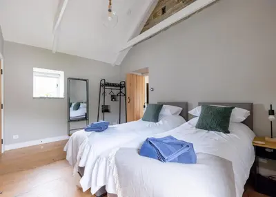 two beds in a room with white walls and wood floors at The Farmhouse - within the Helland Barton Farm collection in Delabole