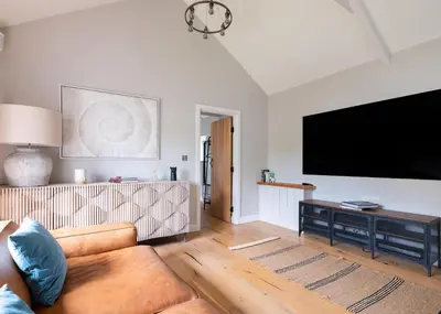 a living room with a couch and a flat screen tv at The Farmhouse - within the Helland Barton Farm collection in Delabole