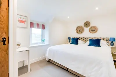 a white bedroom with a bed and a window at Courtyard Cottage - within the Helland Barton Farm collection in Delabole