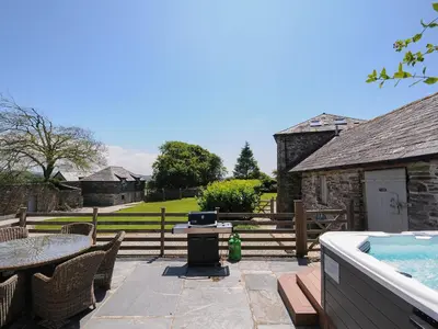a patio with a table and a swimming pool at Courtyard Cottage - within the Helland Barton Farm collection in Delabole