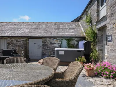 a patio with a table and chairs in front of a building at Courtyard Cottage - within the Helland Barton Farm collection in Delabole