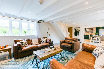 a living room with leather furniture and a table at Courtyard Cottage - within the Helland Barton Farm collection in Delabole
