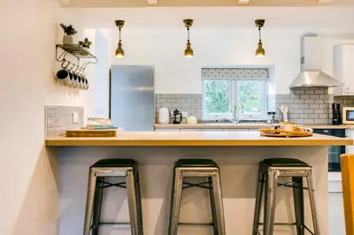 a kitchen with two bar stools at a kitchen counter at The Old Bakehouse - within the Helland Barton Farm collection in Delabole