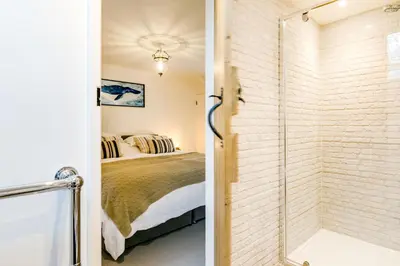 a bathroom with a shower and a bedroom with a bed at The Old Bakehouse - within the Helland Barton Farm collection in Delabole