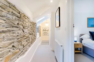 a hallway with a stone wall next to a bedroom at The Old Bakehouse - within the Helland Barton Farm collection in Delabole