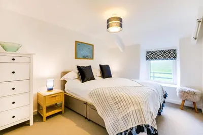 a bedroom with a bed and a dresser and a window at The Old Bakehouse - within the Helland Barton Farm collection in Delabole