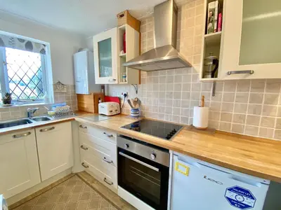 a kitchen with white cabinets and a stove top oven at Heidaway - Padstow in Padstow