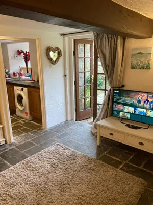 a living room with a flat screen tv and a kitchen at Mill Retreat at Bissick Old Mill in Truro