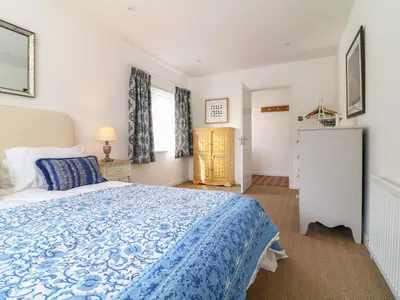 a bedroom with a blue and white bed and a window at Alpha in Wadebridge