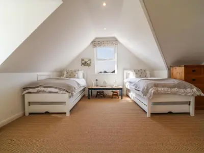 a attic bedroom with two beds and a table at Alpha in Wadebridge