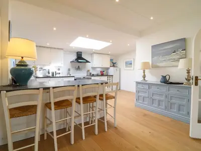 a kitchen with white cabinets and a island with bar stools at Alpha in Wadebridge