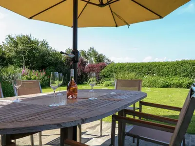 a wooden table with wine glasses and an umbrella at Alpha in Wadebridge