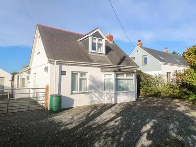 a white house with a green trash can in the driveway at Alpha in Wadebridge