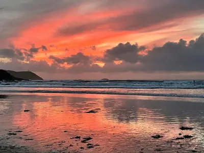 a sunset on a beach with the ocean at Alpha in Wadebridge