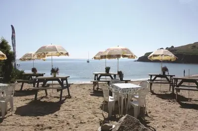 a group of tables and umbrellas on a beach at Luxury Home on Maenporth Estate Next to the Beach in Falmouth