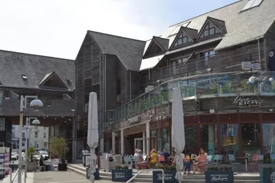 a large building with people sitting outside of it at Luxury Home on Maenporth Estate Next to the Beach in Falmouth