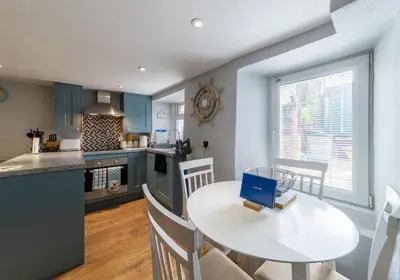 a kitchen and dining room with a white table and chairs at Inviting Traditional Fishermens cottage in the heart of the village, close to the harbour in Mevagissey
