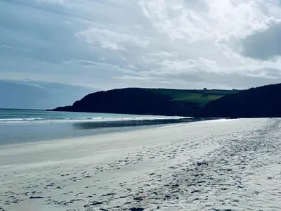 a beach with footprints in the sand and the ocean at Inviting Traditional Fishermens cottage in the heart of the village, close to the harbour in Mevagissey
