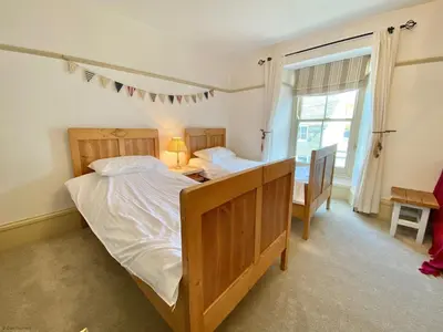 a bedroom with a bed and a desk and a window at Camel Cottage in Padstow