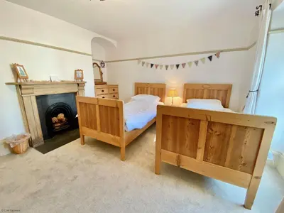 a bedroom with two beds and a fireplace at Camel Cottage in Padstow
