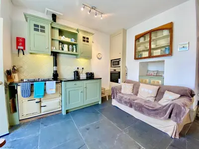 a kitchen with green cabinets and a couch in a room at Camel Cottage in Padstow