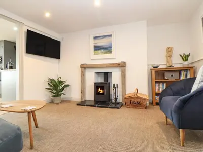 a living room with a fireplace and a blue couch at Ty Bryn in Marazion