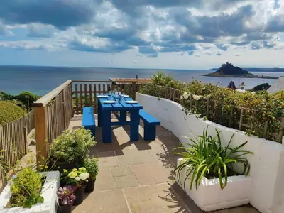 a patio with a blue table and a view of the ocean at Ty Bryn in Marazion