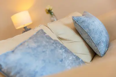 a couch with two blue pillows on it at Beach Haven in Carbis Bay