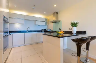 a kitchen with white cabinets and a black counter top at Beach Haven in Carbis Bay