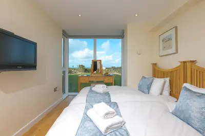 a bedroom with a bed and a tv and a window at Beach Haven in Carbis Bay