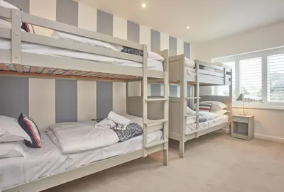 a bedroom with two bunk beds and a window at 5 The Sands in Polzeath