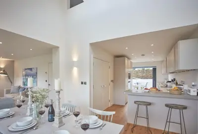 a kitchen and living room with a table and chairs at 5 The Sands in Polzeath