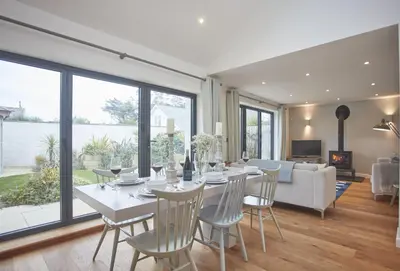 a dining room with a table and chairs and a couch at 5 The Sands in Polzeath
