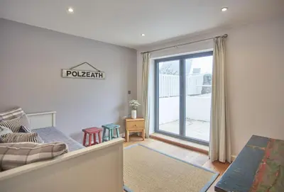 a bedroom with a bed and a sliding glass door at 5 The Sands in Polzeath